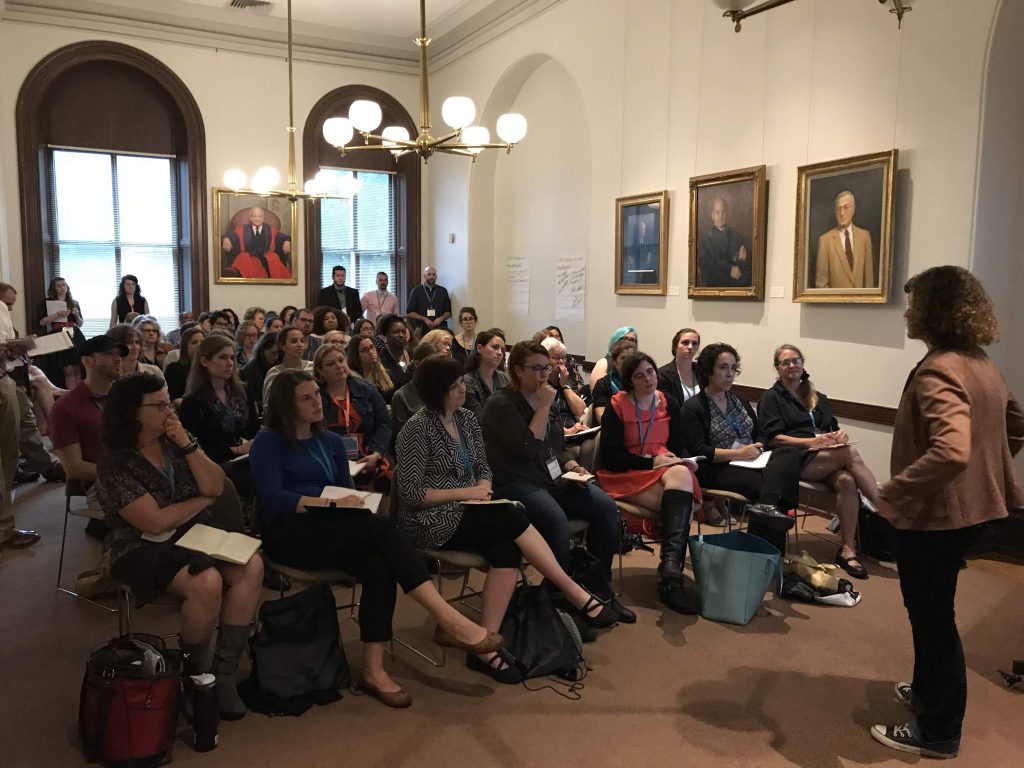 people sitting in a large meeting room watching Molly present